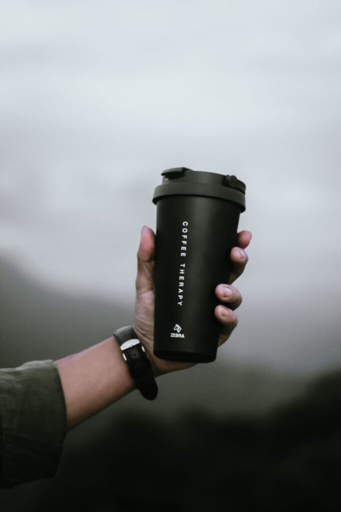 Crafting Captivating Headlines: Your awesome post title goes here Hand holding a black coffee tumbler with 'Coffee Therapy' text against a blurred outdoor background.